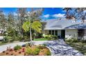 Charming single-story home with lush landscaping, a paved driveway, and a metal roof at 614 Tropical Cir, Sarasota, FL 34242