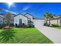Beautiful white home with lush landscaping, palm trees, and well-manicured lawn on a sunny day at 6378 Grandview Hill Ct, Bradenton, FL 34203