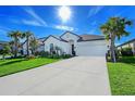 Charming white home with a well-manicured lawn, beautiful landscaping, and a spacious driveway on a sunny day at 6378 Grandview Hill Ct, Bradenton, FL 34203