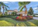 A charming single-story home with meticulously landscaped yard featuring vibrant flowers and mature palm trees at 7108 Callander Cv, Lakewood Ranch, FL 34202