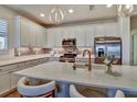 Bright kitchen featuring white cabinetry, stainless steel appliances, an island with seating, and stylish backsplash at 8192 Sternway Rd, Sarasota, FL 34240