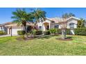 Well-maintained house exterior with a green lawn, palm trees, and manicured landscaping on a sunny day at 11031 Hyacinth Pl, Lakewood Ranch, FL 34202