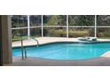 Relaxing screened-in pool with a spill-over spa and clear blue water, set against a lush green backdrop at 629 Sawgrass Bridge Rd, Venice, FL 34292