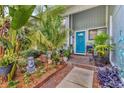 Up-close front entrance featuring a blue door, brick walkway, and lush, tropical landscaping at 7892 S Leewynn Pl, Sarasota, FL 34240