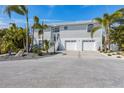 Coastal two-story home featuring mature palms and a two-car garage at 9 Palm Harbor Dr, Holmes Beach, FL 34217