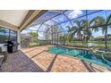 A screened-in pool overlooks a serene lake surrounded by lush landscaping at 13112 Ramblewood Trail, Bradenton, FL 34211