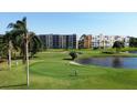 Golf course putting green, pond, and condominiums under a sunny sky offer a tranquil atmosphere at 3750 Pinebrook Circle # Apt 505, Bradenton, FL 34209