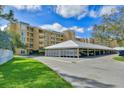 View of covered parking area and the exterior of the condo building with lush green lawn and blue skies at 3750 Pinebrook Circle # Apt 505, Bradenton, FL 34209
