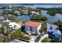 Stunning waterfront home with a red tile roof, lush landscaping, and a beautiful view of the surrounding water at 4205 Higel Ave, Sarasota, FL 34242