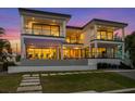 Expansive rear view of a modern home featuring multiple balconies and outdoor seating areas at 7003 Holmes Blvd, Holmes Beach, FL 34217