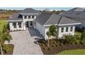 Well-manicured exterior showcasing a three-car garage, brick driveway, and a beautifully landscaped lawn at 8364 Sea Glass Ct, Sarasota, FL 34240