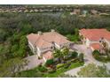 Aerial view showcasing the home's tile roof, lush landscaping, and brick driveway at 9460 Discovery Ter # 202D, Bradenton, FL 34212