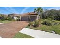 Charming house featuring a clay tile roof, two-car garage, and a paver driveway at 10802 Seasons Way, Palmetto, FL 34221