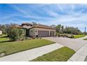 Single-story home featuring a two-car garage, clay tile roof, and landscaped front yard at 10802 Seasons Way, Palmetto, FL 34221