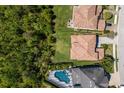This is a sunny aerial view of several houses featuring an in-ground pool and green foliage at 12022 Medley Ter, Lakewood Ranch, FL 34211