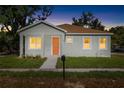 Inviting single-story home featuring a bright orange front door and a well-maintained lawn at dusk at 1301 12Th S St, St Petersburg, FL 33705
