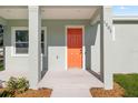 Inviting front porch with a bright orange door, modern column supports and fresh landscaping at 1301 12Th S St, St Petersburg, FL 33705