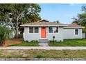 Inviting single-story home boasts a light-blue exterior, orange front door and a neatly maintained lawn at 1739 16Th S Ave, St Petersburg, FL 33712