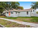 Well-kept single-story home featuring light-blue siding, an orange front door, and a green lawn at 1739 16Th S Ave, St Petersburg, FL 33712