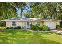 Charming yellow home with lush landscaping, a brick-paved driveway, and mature shade trees at 1870 Jasmine Dr, Sarasota, FL 34239