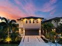 Stunning two-story home with a modern design, lush landscaping, and a spacious driveway at twilight at 2305 Pine Ter, Sarasota, FL 34231