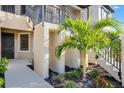 Unit entrance with a black door, lush landscaping including palm tree and visible staircase at 23445 Collina Way # 10103, Port Charlotte, FL 33980