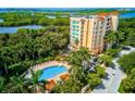 Aerial view of the community featuring a pool, lush landscaping, and multi-story buildings on the waterway at 3603 N Point Rd # 702, Osprey, FL 34229