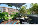 Charming patio area with bench seating, colorful flooring, and lush greenery surrounding the condo building at 4133 Heron Way # E202, Bradenton, FL 34205