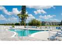 Beautiful community pool with lounge chairs and shade trees on a sunny day with blue skies and white clouds at 4133 Heron Way # E202, Bradenton, FL 34205