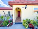 Inviting entryway featuring a red front door, arched entrance, and vibrant landscaping at 916 W Faith Cir, Bradenton, FL 34212