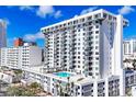A condominium building showcasing architectural design, with a rooftop pool and an American flag, against a clear blue sky at 101 S Gulfstream Ave # 14G, Sarasota, FL 34236