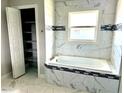 Luxurious soaking tub with a tiled surround, complemented by built-in storage and a window at 1056 Tampa Rd, Venice, FL 34293