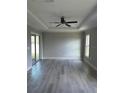 Bright living room featuring elegant wood-look flooring, ample natural light, and a modern ceiling fan at 1056 Tampa Rd, Venice, FL 34293