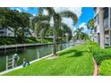 Scenic waterfront view with lush green lawn, mature palm trees, and a canal at 1350 N Portofino Dr # 108, Sarasota, FL 34242