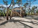Exterior view of elevated beach home surrounded by tropical foliage and mature landscaping at 3376 S Seclusion Dr, Sarasota, FL 34239