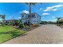 Elegant two-story residence featuring a brick-paved driveway, lush landscaping, and attached three-car garage at 4789 Vasca Dr, Sarasota, FL 34240