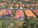 Aerial view showcasing tile roofs, screened lanai, and a picturesque pond in a residential community at 5142 Cote Du Rhone Way, Sarasota, FL 34238