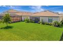 Lush green backyard featuring healthy grass and manicured shrubs with screened lanais in view at 5317 Coral Reef Way, Bradenton, FL 34211