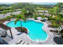 Aerial view of a large community pool with a splash pad, lounge chairs, and lush tropical landscaping at 5778 Windy Bay Ter, Nokomis, FL 34275