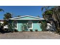 Charming single story house with turquoise stucco exterior, white trim, arched windows, and brick driveway at 5802 De Palmas Ave, Holmes Beach, FL 34217