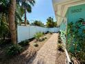 Landscaped side yard and brick walkway with lush foliage and a white vinyl privacy fence at 5802 De Palmas Ave, Holmes Beach, FL 34217