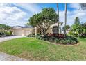 Well-maintained lawn and landscaping complement this home's exterior, complete with palm trees and colorful flower beds at 6215 Aventura Dr, Sarasota, FL 34241