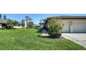 Residential home featuring manicured landscaping, green lawn, and a paved driveway to a garage at 7347 Royal Birkdale Dr, Sarasota, FL 34238