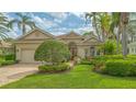 Stunning front view with lush landscaping, beautiful lawn, and a charming red door providing a welcoming entrance to the home at 7432 Ascot Ct, University Park, FL 34201