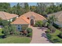 Charming one-story home with a red tile roof, brick paved driveway, and lush tropical landscaping at 7762 Us Open Loop, Lakewood Ranch, FL 34202