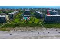 Aerial view of beachfront condo building, community pool and tropical landscaping at 1055 Gulf Of Mexico Dr # 405, Longboat Key, FL 34228