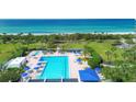 Beautiful aerial view of community pool, sun loungers, tropical landscaping, and turquoise ocean at 1055 Gulf Of Mexico Dr # 405, Longboat Key, FL 34228