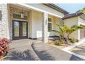 Stunning front entryway featuring a tiled porch, stone accents and a large wooden double door at 115 Solana St, North Port, FL 34287