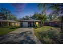 Home at dusk featuring a front lawn, attached garage, and mature landscaping at 1410 24Th E Ave, Bradenton, FL 34208