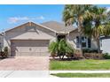 Beautiful single-story home with a brick driveway, a well-kept lawn and mature palm trees in landscaped front yard at 14355 59Th E Cir, Bradenton, FL 34211